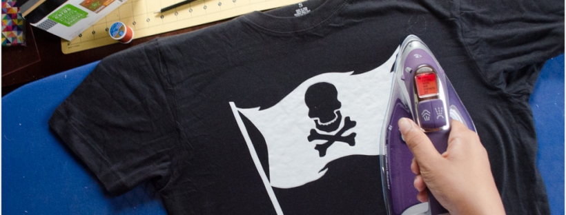 Ironing Jolly Roger pirate flag stencil onto black tee shirt for DIY bleach spray pirate shirt
